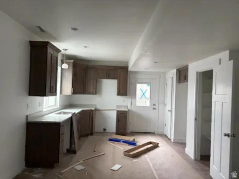 Kitchen featuring dark wood-finish cabinetry, light-toned countertops, recessed lighting, and a pendant fixture