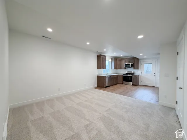 Recessed lighting, wood-finish flooring, light-toned carpet, stainless steel appliances, and wood-finish cabinetry
