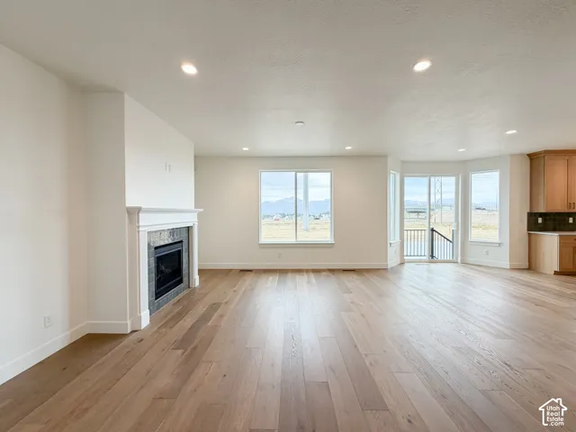 Expansive room featuring wood-finish flooring, a built-in fireplace with a tile surround and mantel, and multiple windows