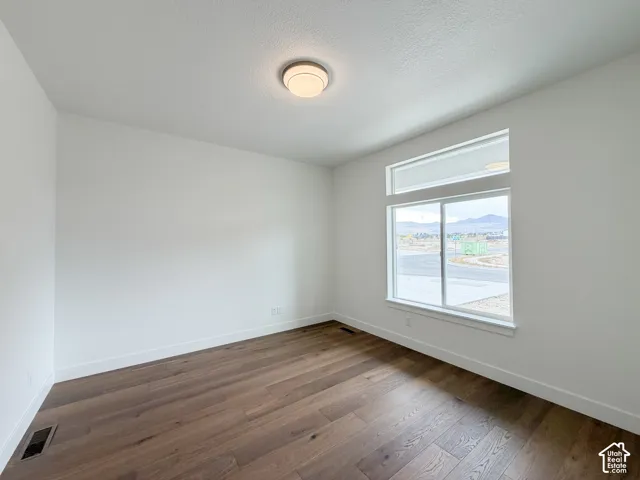 Wood-finish flooring, white walls, and a large window with an upper transom