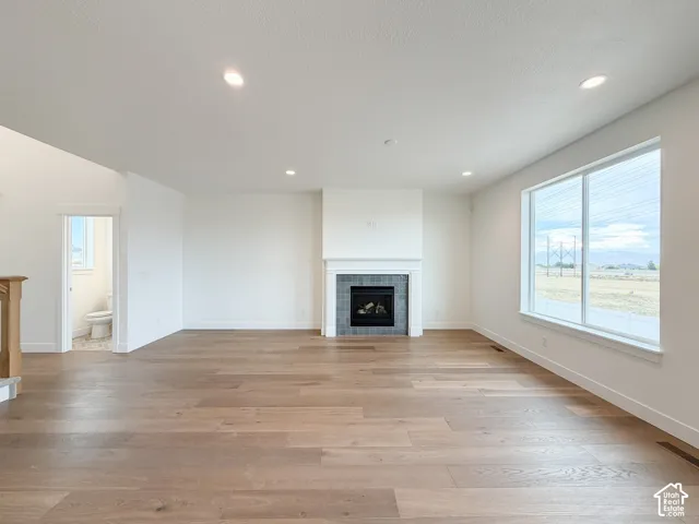 Spacious living area featuring wood-finish flooring, a fireplace with a tile surround, and recessed lighting