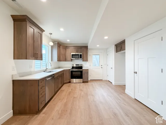Kitchen featuring wood-finish flooring, recessed lighting, wood cabinetry, stainless steel appliances, and light-toned countertops