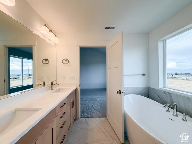 Dual vanity with rectangular undermount sinks, wood-finish cabinetry, and a freestanding soaking tub
