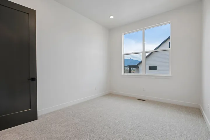White walls, recessed lighting, gray carpet flooring, matte black door, and a multi-pane window