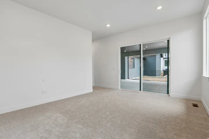 Recessed lighting, large sliding glass door, white trim, light-colored carpeting, and a window with white casing