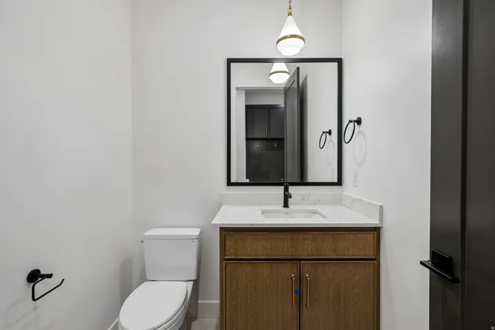 Vanity with wood-finish cabinetry, white countertop, and integrated sink