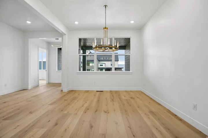 Spacious room featuring wood-finish flooring, a contemporary chandelier, and recessed lighting