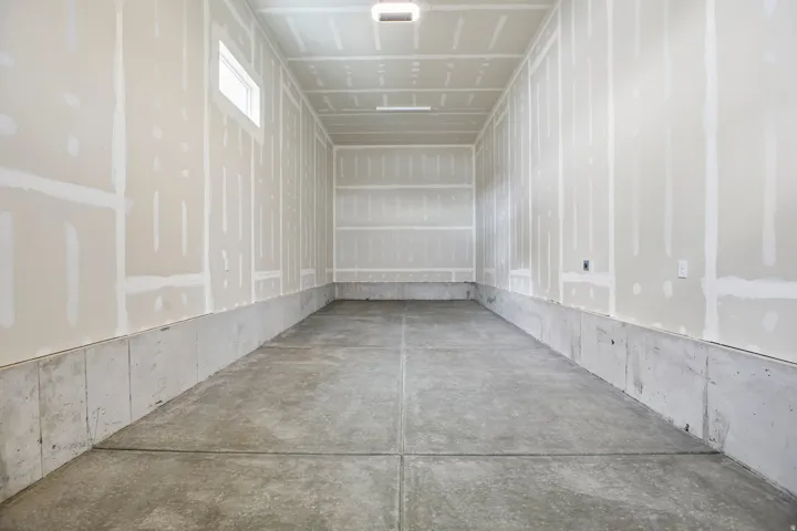 Concrete flooring, unfinished walls, ceiling lighting, and a transom window