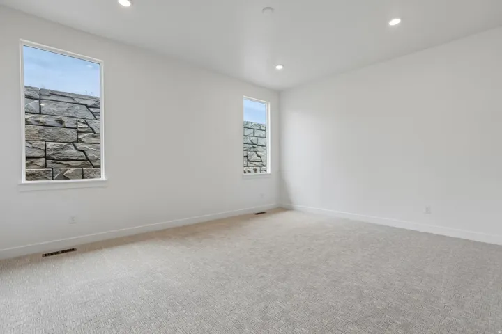 Recessed lighting illuminates this bright room featuring light-toned carpeting and white walls