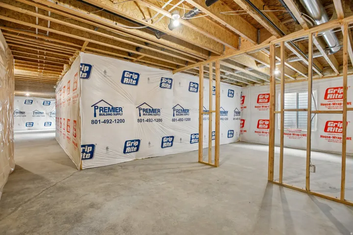 Unfinished basement with exposed ceiling joists, concrete flooring, and framed interior walls