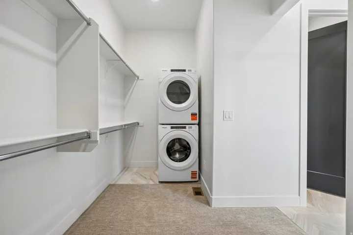 Integrated laundry appliances, built-in shelving, chrome hanging rods, recessed lighting, and mixed flooring