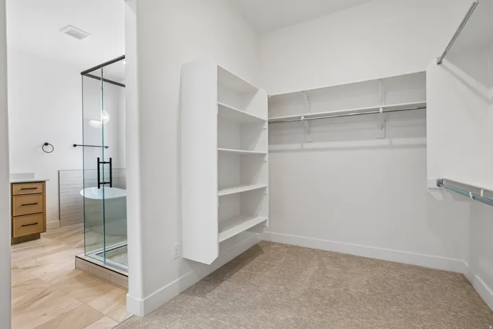 Walk-in closet with built-in shelving, hanging rods, and carpet flooring