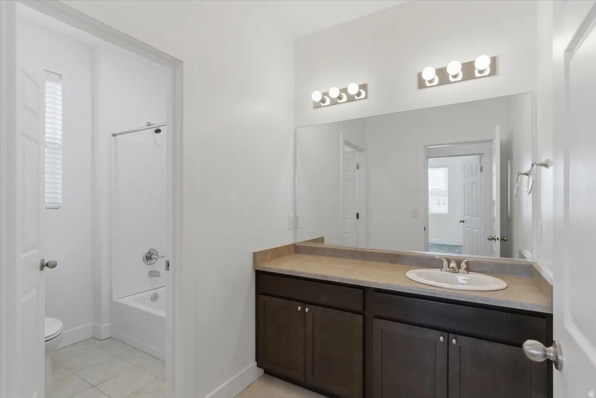 Bathroom featuring a single vanity with a white oval sink, dark wood-finish cabinetry, and a light-toned countertop