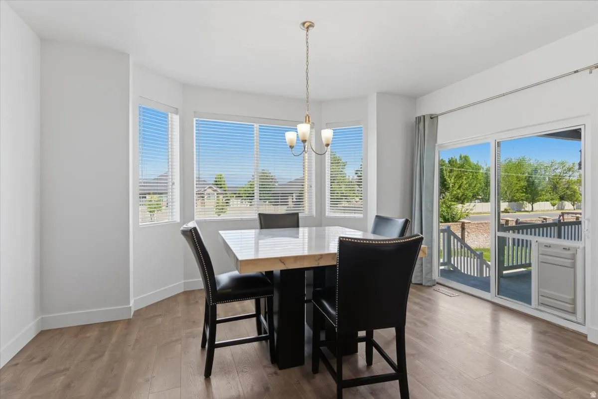 Dining area featuring wood-finish flooring, a bay window with blinds, and a sliding glass door providing access to an exterior deck