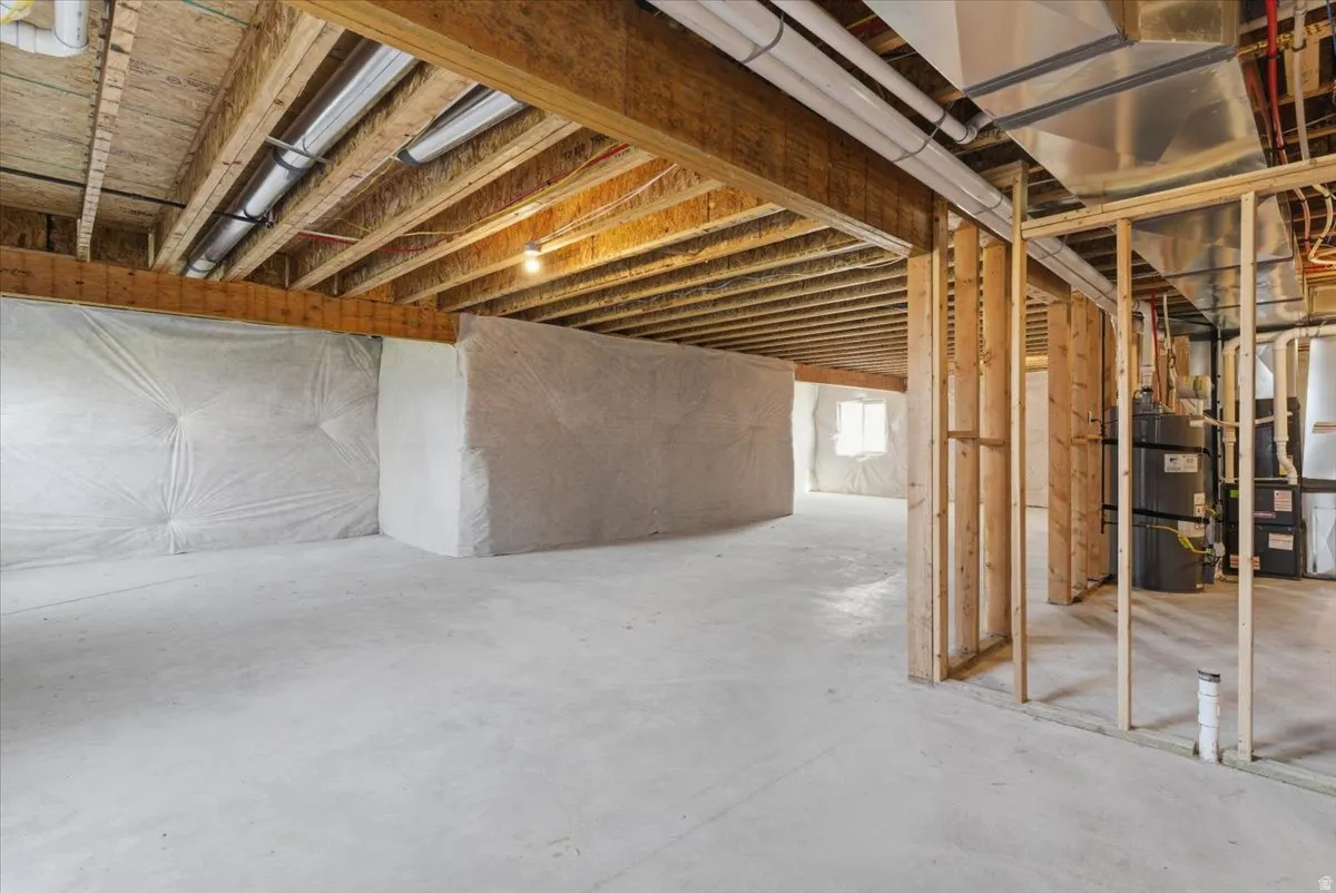 Unfinished lower level with concrete flooring, exposed wood joists, and framed partition walls