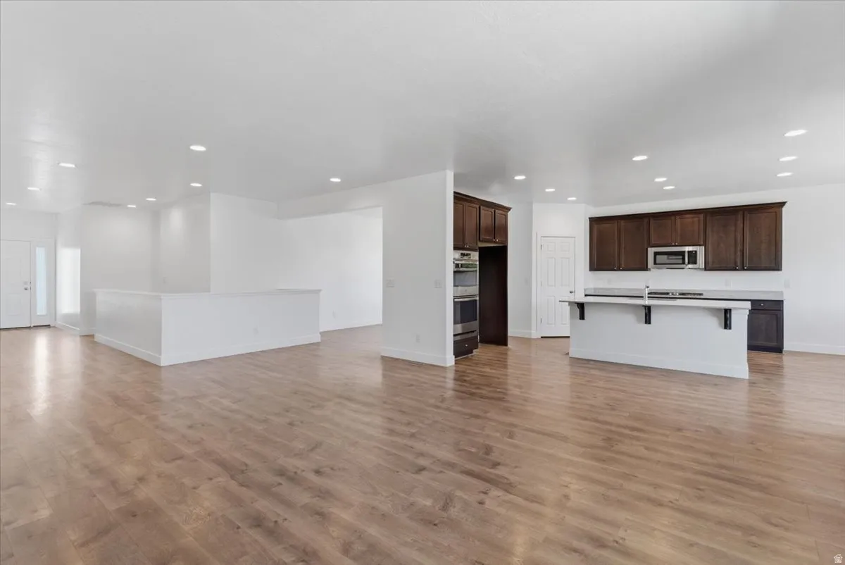 Open-concept living area featuring wood-finish flooring, recessed lighting, and a kitchen with dark wood cabinetry