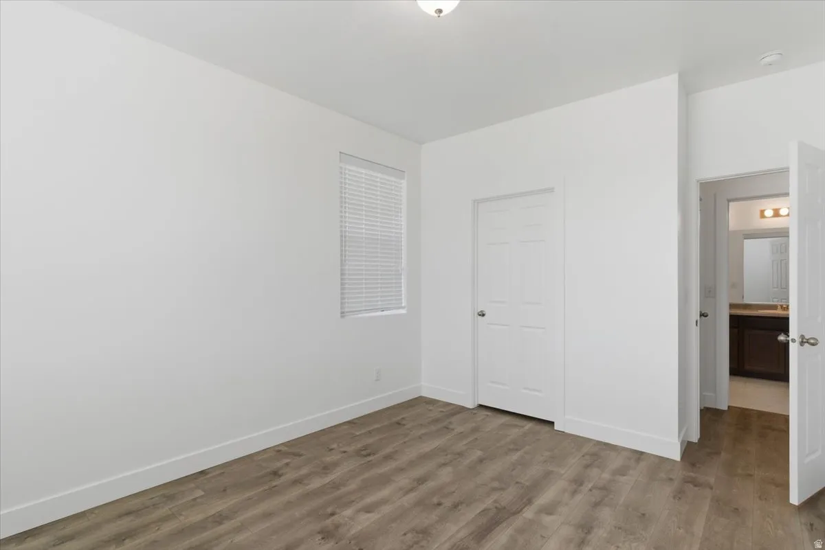 Bright room featuring wood-finish flooring, white walls, and a window with blinds