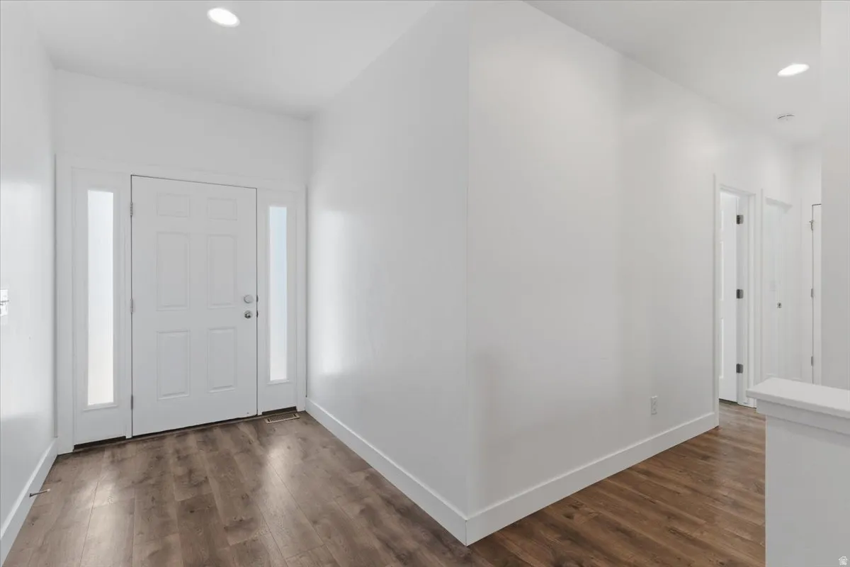 Entryway featuring a white paneled door with frosted sidelights, recessed lighting, wood-finish flooring, and crisp white walls