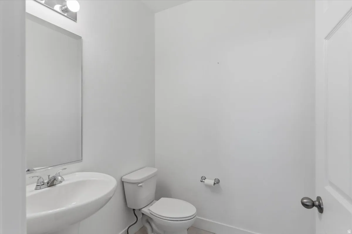 Pedestal sink with chrome faucet, large wall mirror, and vanity light fixture
