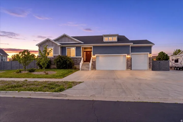 Contemporary residence featuring blue siding, stone accents, and a prominent three-car garage