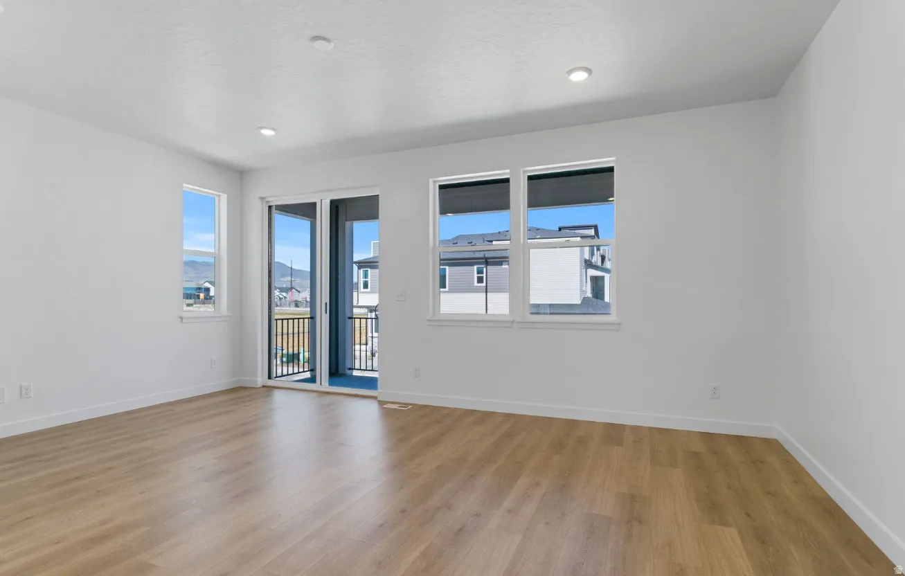 Expansive room featuring wood-finish flooring, white walls, and recessed lighting