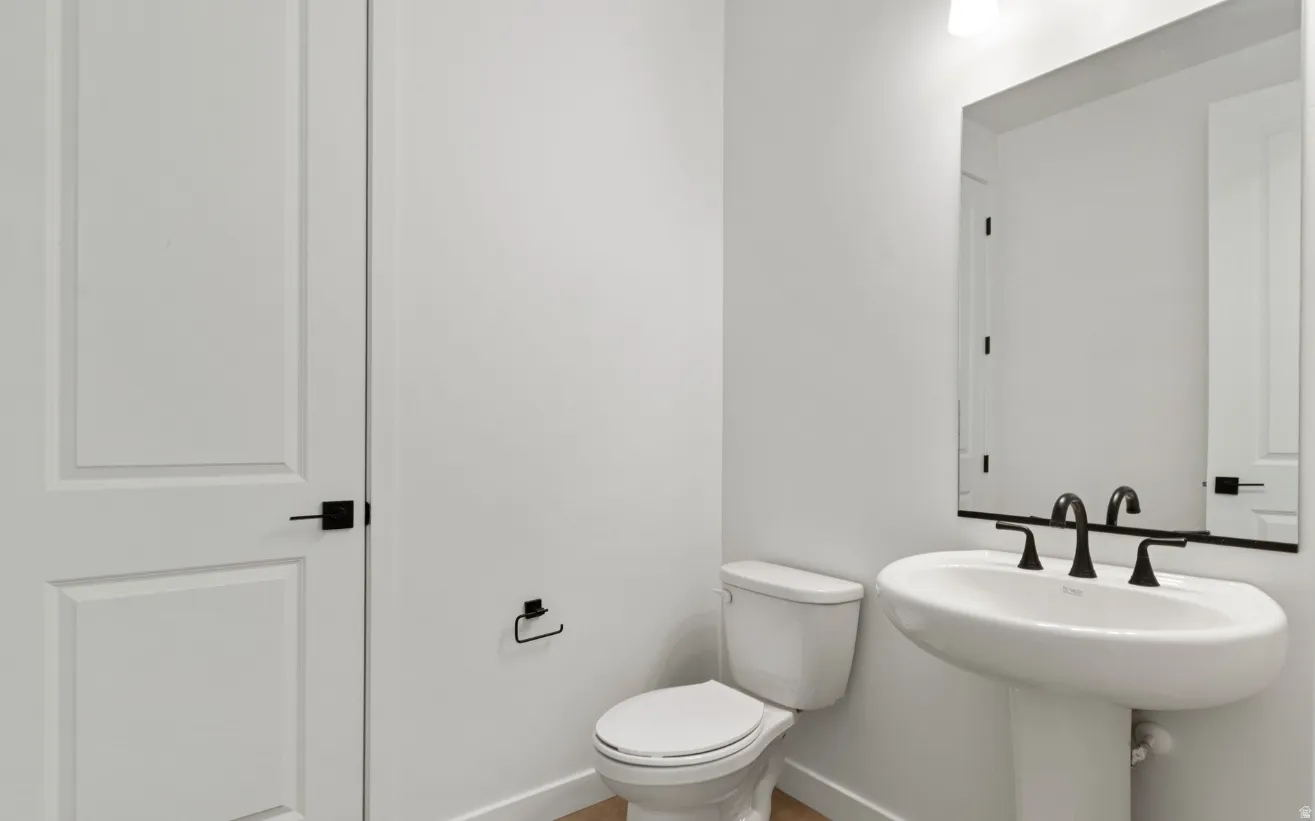 Pedestal sink with matte black faucet, framed mirror, and modern panel door with black hardware