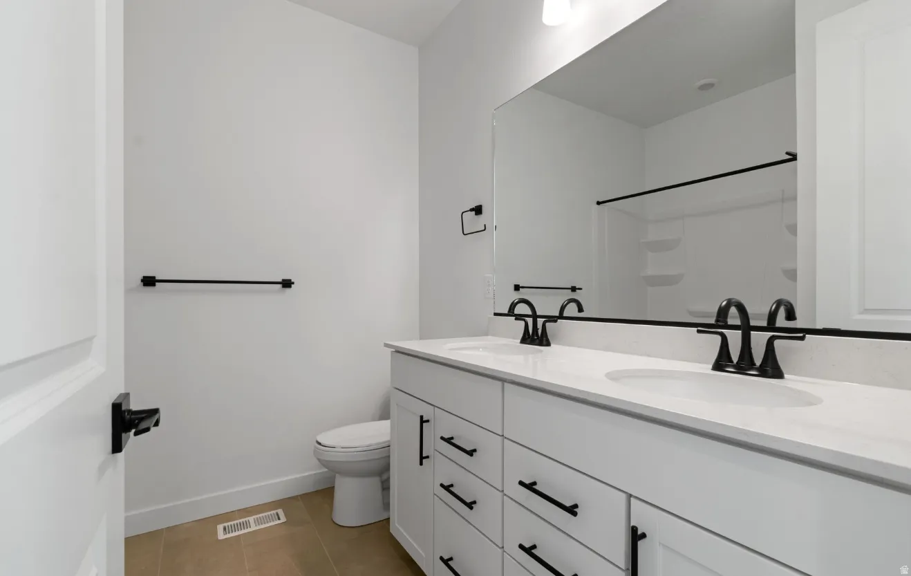 Bathroom featuring a double vanity with white cabinetry, a light-colored countertop, and matte black fixtures