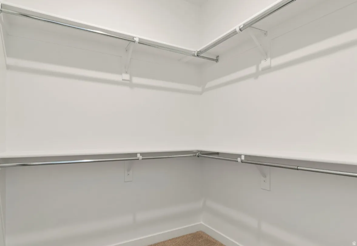 Walk-in closet featuring white walls, integrated shelving, and metal hanging rods