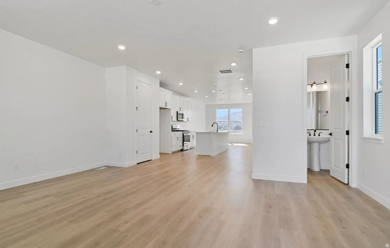 Open concept living space featuring light wood-finish flooring and recessed lighting