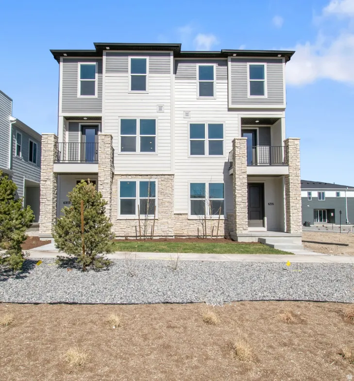 Modern multi-story exterior featuring a stone facade and horizontal siding
