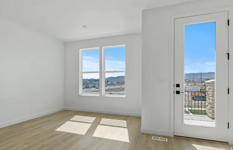 Bright room featuring wood-finish flooring, white walls, and white baseboards