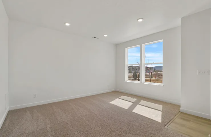 Bright room featuring two large windows, recessed ceiling lighting, and neutral-toned carpeting