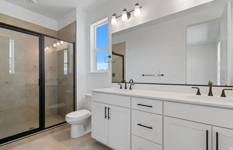 Bathroom featuring a dual vanity with white cabinetry, integrated sinks, and bronze-finish fixtures
