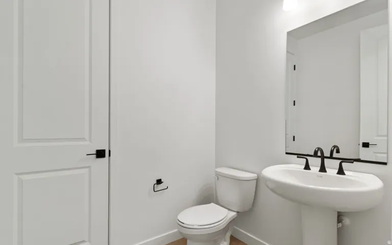 Pedestal sink with matte black faucet, framed mirror, and modern panel door with black hardware