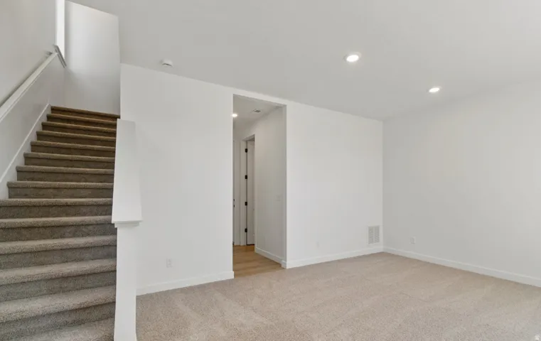 Neutral tone carpet flooring and crisp white walls characterize this interior space, featuring a staircase with matching carpet treads and a white handrail