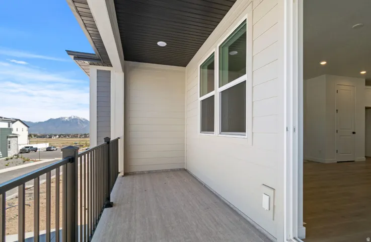 Outdoor balcony featuring a metal railing, wood-finish flooring, and white siding