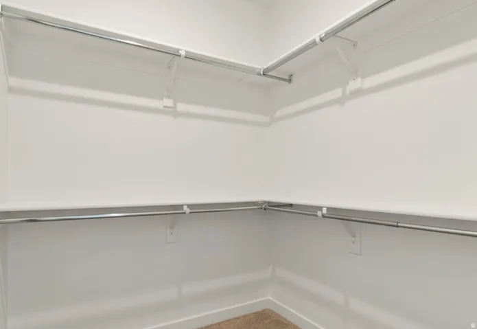 Walk-in closet featuring white walls, integrated shelving, and metal hanging rods