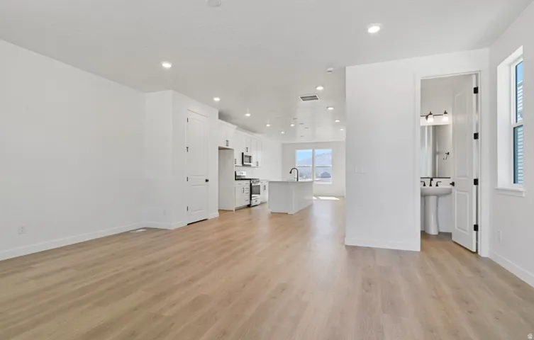 Open concept living space featuring light wood-finish flooring and recessed lighting