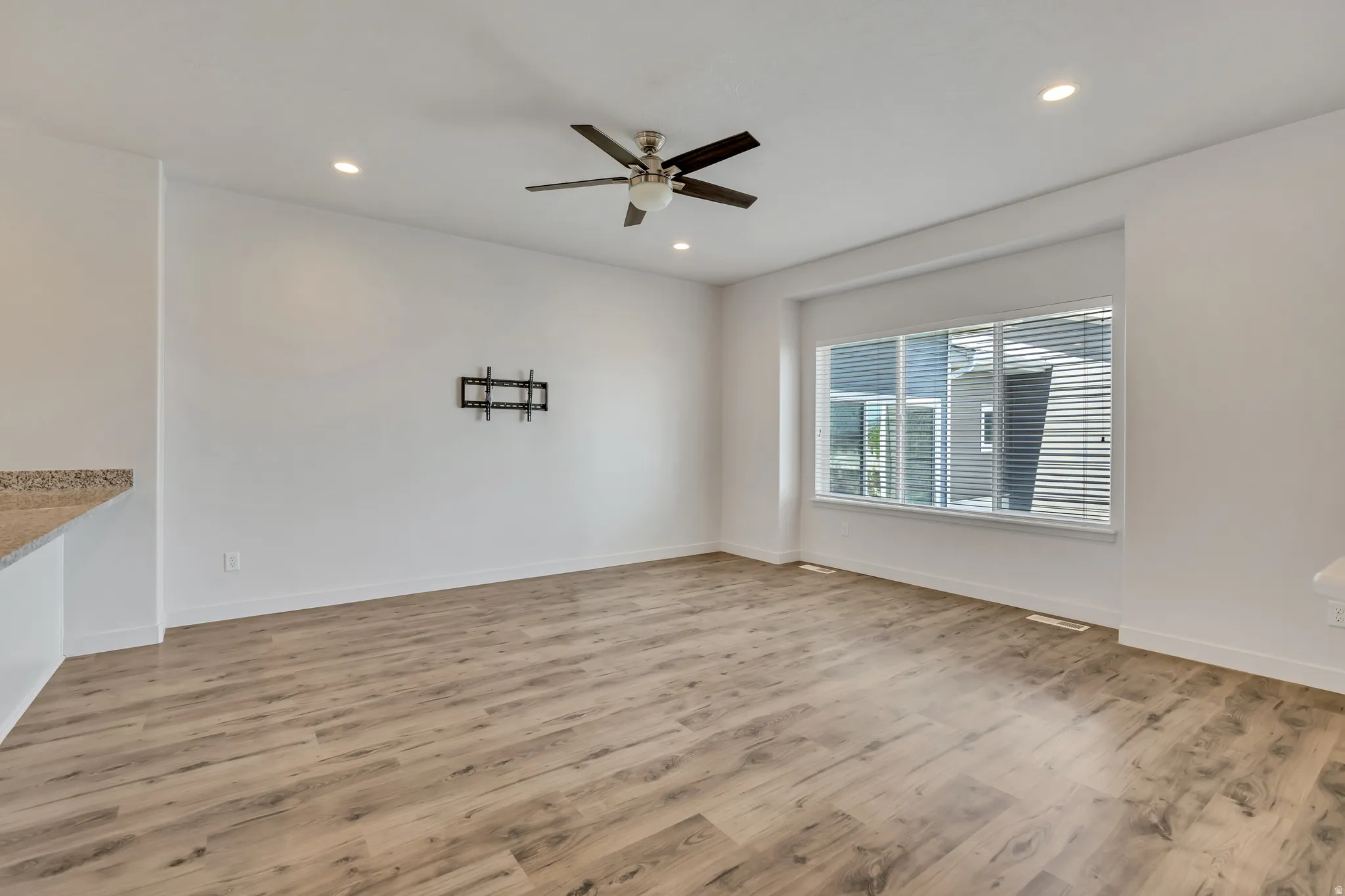Spacious room featuring wood-finish flooring, recessed lighting, and a contemporary ceiling fan