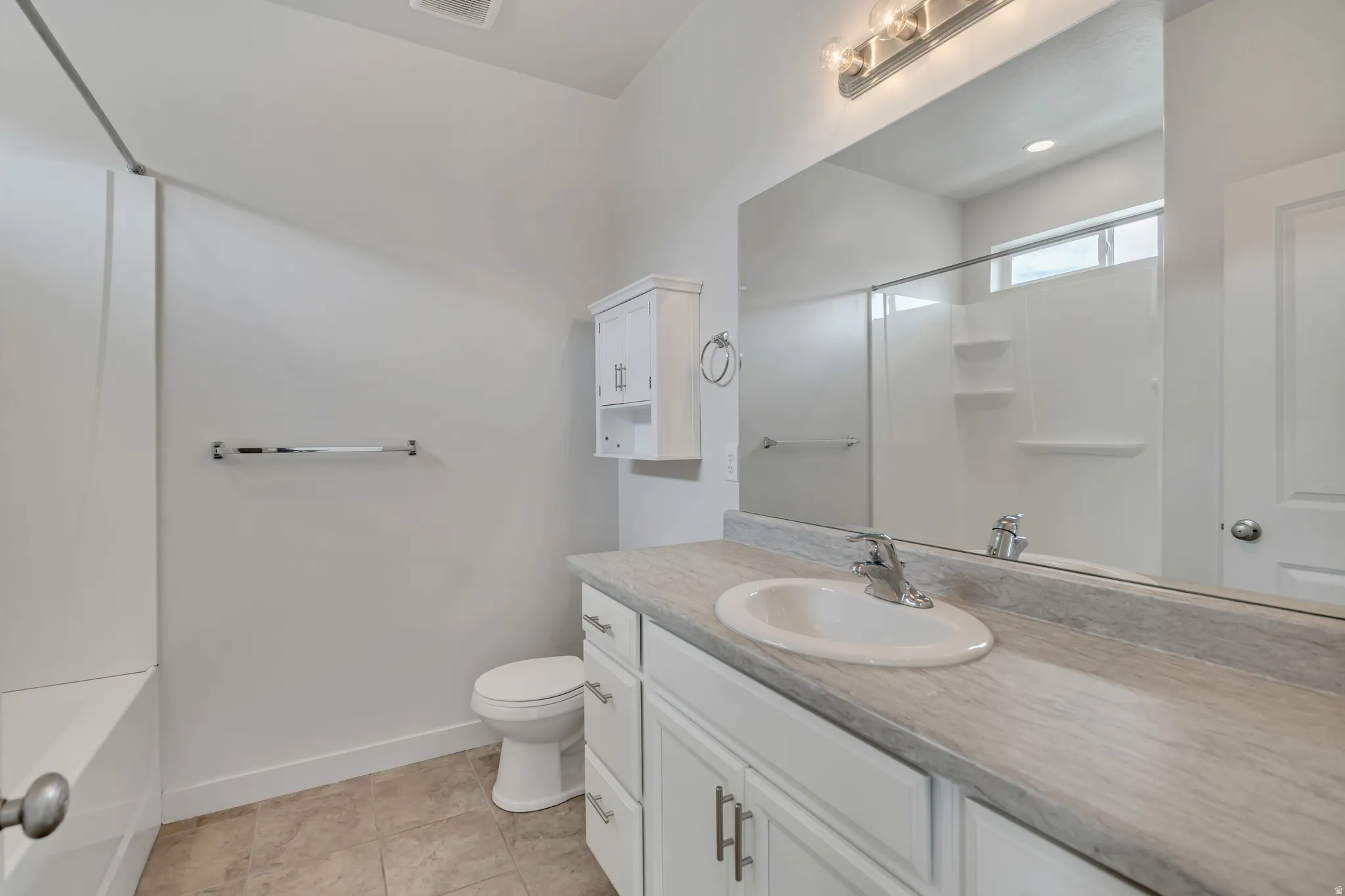 Bathroom featuring a white vanity with an integrated sink, a large mirror, and a shower-tub combination with a sliding glass door