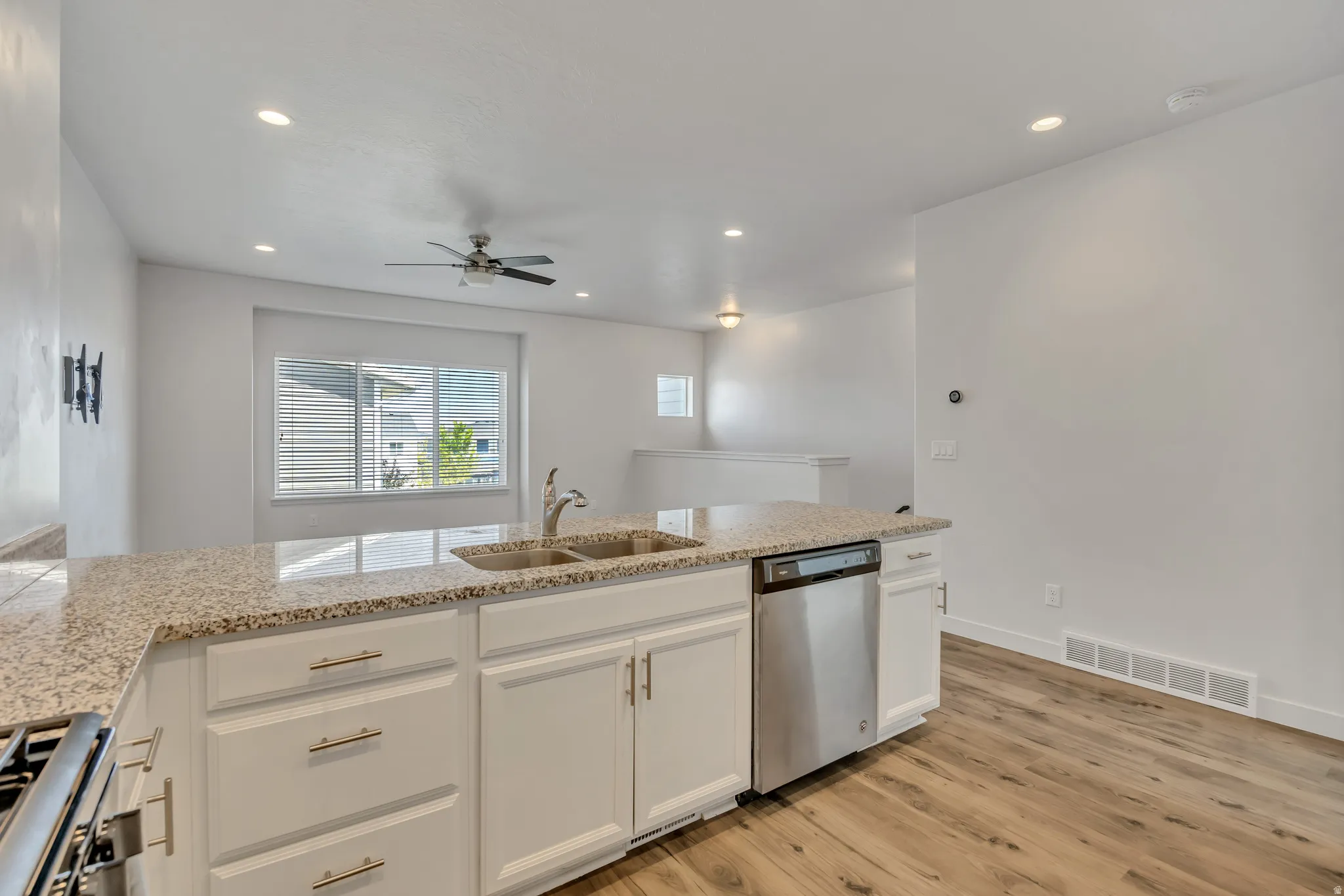 Kitchen island featuring a double basin sink, granite-style countertop, and stainless steel dishwasher