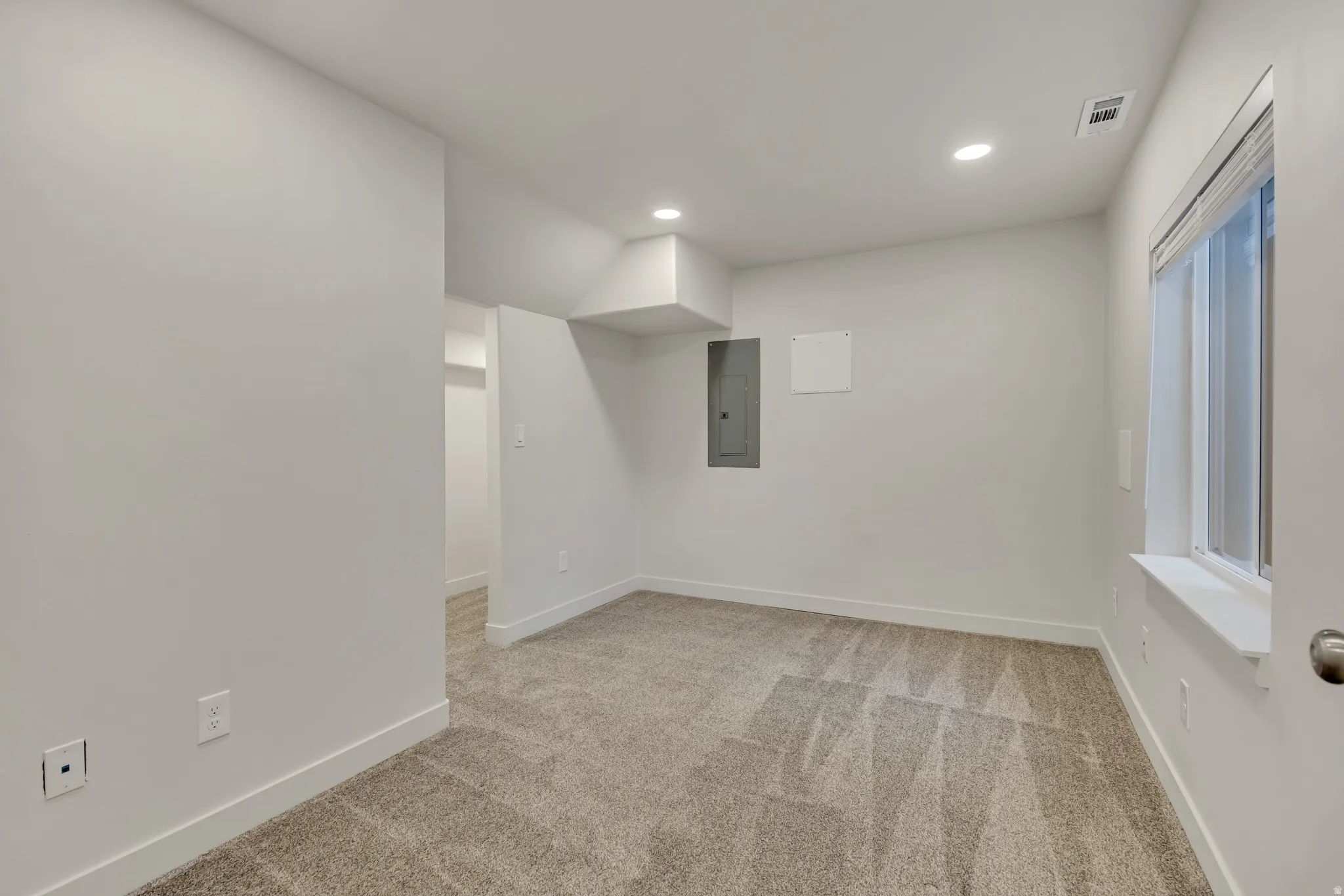 Carpeted room with recessed lighting and a window