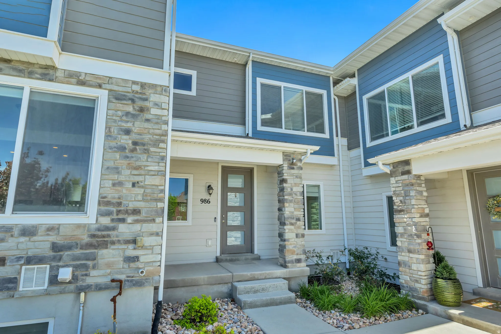 Modern exterior featuring stone veneer accents, multi-pane windows, and a covered entry with stone-wrapped columns