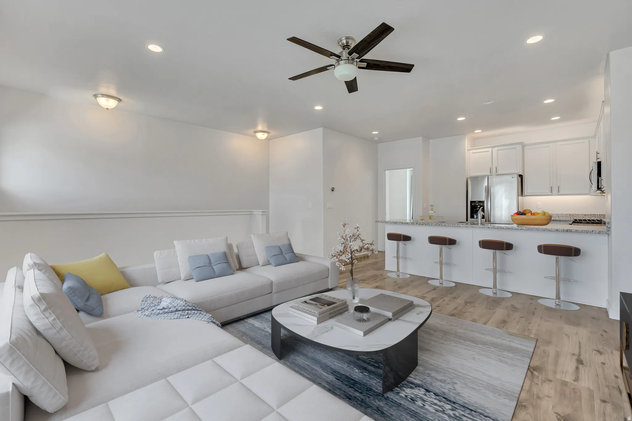 Open-concept living space featuring wood-finish flooring and a ceiling fan with integrated lighting