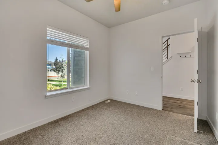 Bright room with neutral carpeting, white walls, and a large window with horizontal blinds