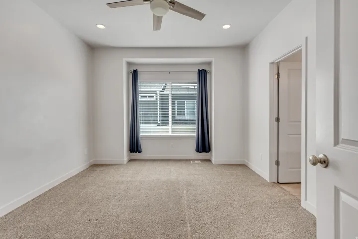 Carpeted interior space featuring a recessed window, a ceiling fan with integrated lighting, and recessed ceiling lights