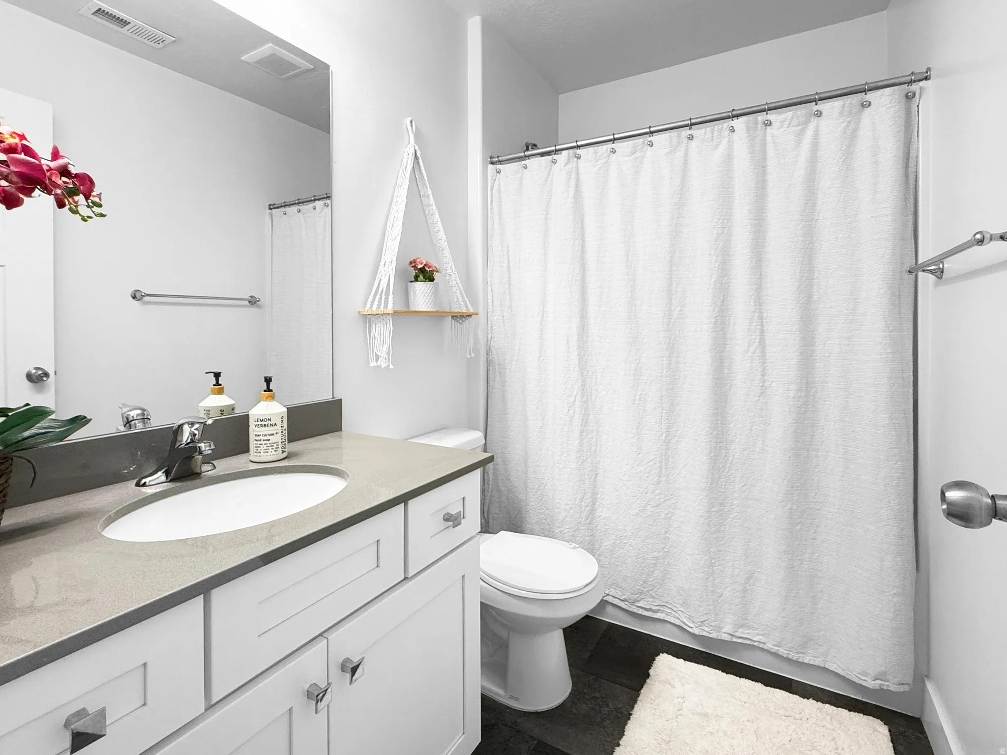 Bathroom featuring a white vanity with shaker-style cabinetry, a light-toned countertop, and an undermount sink