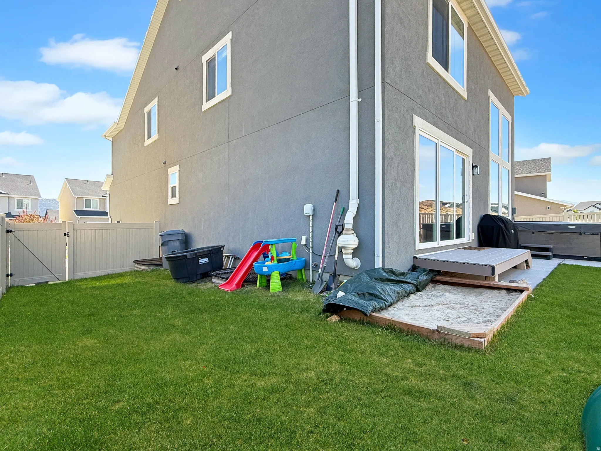 Manicured lawn with a privacy fence, a concrete patio, a raised deck, and a built-in sandbox
