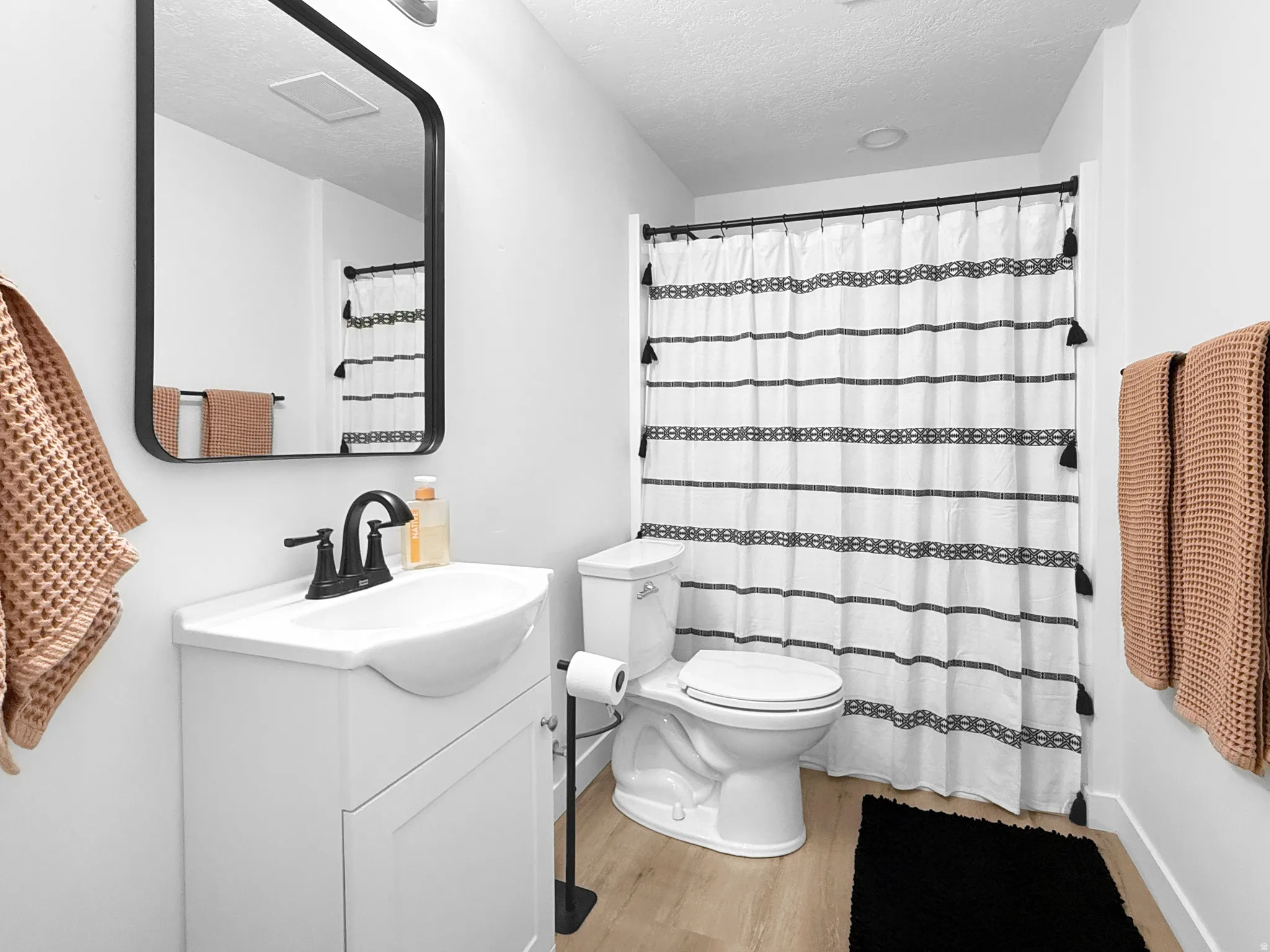 Bathroom featuring a white vanity with integrated sink, matte black faucet, and a wall-mounted rectangular mirror