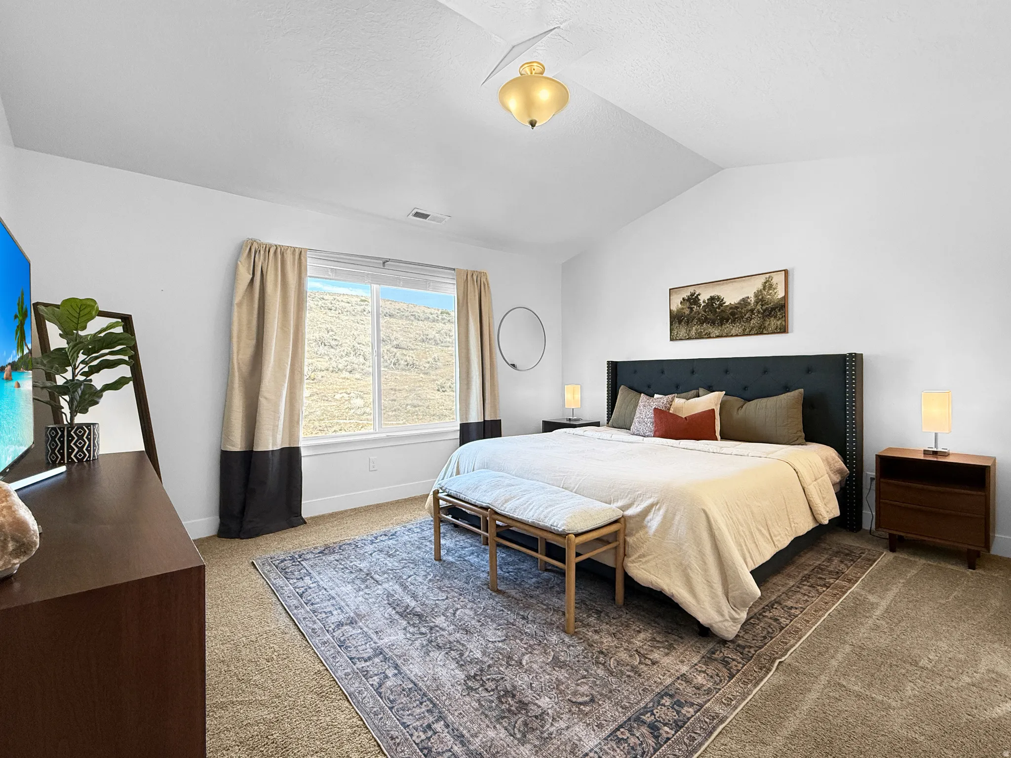 Spacious bedroom featuring vaulted ceilings, a window with outdoor scenery, and neutral wall-to-wall carpeting